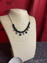 Load image into Gallery viewer, Shimmery silver heart charms, silver beads, and polished black beads swing from a row of matching black beads, creating a whimsical fringe below the collar. Featuring a regal teardrop shape, a glittery white rhinestone swings from the center for a refined finish. Features an adjustable clasp closure.  Sold as one individual necklace. Includes one pair of matching earrings.