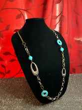 Load image into Gallery viewer, A compilation of refreshing turquoise stone beads, silver rings, brass rings, and hammered silver accents connect across the chest for an artisan flair. Features an adjustable clasp closure.  Sold as one individual necklace. Includes one pair of matching earrings.  Always nickel and lead free.