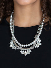 Load image into Gallery viewer, A classic strand of silver pearls and dramatic silvery chain drape below the collar. Infused with heavy metal accents, teardrop and marquise cut white rhinestone frames connect into a show-stopping fringe. Features an adjustable clasp closure.  Sold as one individual necklace. Includes one pair of matching earrings.
