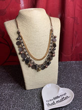 Load image into Gallery viewer, Varying in shape and shimmer, a mishmash of copper, gold and gunmetal chains layer below the collar. Infused with classic gold, copper and gunmetal beads, textured copper discs swing from the bottom of the lowermost chain, creating a playful fringe. Features an adjustable clasp closure.  Sold as one individual necklace. Includes one pair of matching earrings.   Always nickel and lead free.