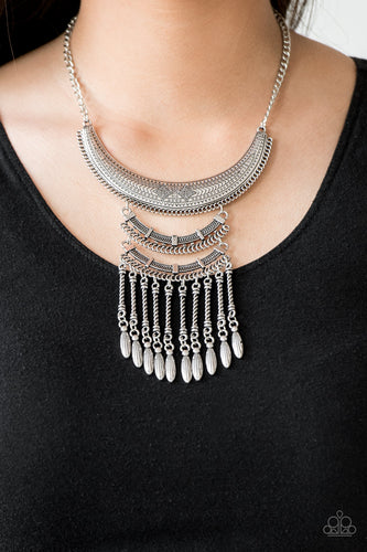 Stamped and embossed in tribal inspired patterns, three silver plates connect down the chest, creating a fiercely stacked pendant. Attached to twisted silver rods, ornate silver beads swing from the bottom of the lowermost plate, creating an eye-catching fringe. Features an adjustable clasp closure.  Sold as one individual necklace. Includes one pair of matching earrings.  Always nickel and lead free.