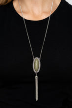 Load image into Gallery viewer, An oval Military Olive stone is pressed into a glistening silver frame stamped in antiqued tribal inspired patterns. A shimmery silver chain tassel swings from the bottom of the earthy pendant for a whimsical finish. Features an adjustable clasp closure.  Sold as one individual necklace. Includes one pair of matching earrings.  