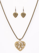 Load image into Gallery viewer, An airy heart swings from the bottom of a shimmery brass cocoon chain, creating a whimsical pendant below the collar. Brushed in an antiqued shimmer, frilly filigree climbs the heart frame for a vintage inspired finish. Features an adjustable clasp closure.  Sold as one individual necklace. Includes one pair of matching earrings. 