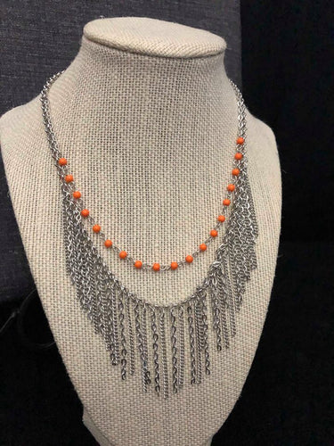 Dainty orange beads swing gently from a silver chain,  with a bold fringe below the collar for a fun look. Features an adjustable clasp closure.  Sold as one individual necklace. Includes one pair of matching earrings.  Always nickel and lead free.  Exclusive