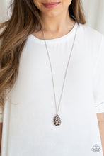 Load image into Gallery viewer, Stenciled in a whimsical floral pattern, an airy silver teardrop frame overlaps a glowing brown cat's eye stone, creating a colorful pendant at the bottom of a lengthened silver chain. Features an adjustable clasp closure.  Sold as one individual necklace. Includes one pair of matching earrings.  Always nickel and lead free.