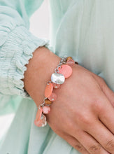 Load image into Gallery viewer, Springtime charms of shiny and soft beads and pearl-like discs in lovely tones of Burnt Coral sway from a silver chain. Accents of sparkly, wavy silver discs and wooden beads bring it down to earth as the fringe wraps around the wrist. Features an adjustable clasp closure..