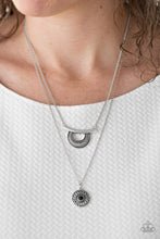 Load image into Gallery viewer, Radiating with linear patterns, a shimmery silver frame swings from the uppermost chain above a silver disc radiating with floral detail. A dainty black bead dots the center of the lowermost pendant for a colorful finish. Features an adjustable clasp closure.  Sold as one individual necklace. Includes one pair of matching earrings.  Always nickel and lead free.