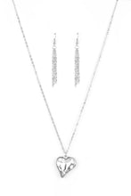 Load image into Gallery viewer, Chiseled into a charming heart, an over sized white rhinestone gem is nestled inside a sleek silver frame, creating a flirtatious pendant below the collar. Features an adjustable clasp closure. Sold as one individual necklace. Includes one pair of matching earrings.