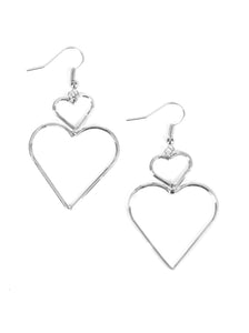 A large silver heart silhouette swings from the bottom of a dainty silver heart silhouette, creating a charming lure. Earring attaches to a standard fishhook fitting.  