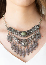 Load image into Gallery viewer, Featuring a collision of hammered, studded, and embossed patterns, two silver half-moon plates dramatically stack below the collar. Swirling with studded filigree detail, ornate silver frames swing from the bottoms of the stacked pendants, creating a fierce tribal inspired fringe. An earthy green stone is pressed into the center of the uppermost frame for a seasonal finish. Features an adjustable clasp closure.  Sold as one individual necklace. Includes one pair of matching earrings.