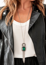Load image into Gallery viewer, An oversized emerald green gem is pressed into the center of an antiqued silver pendant radiating with ornate detail. Rounded silver snake chains stream from the bottom of the heirloom inspired pendant for a vintage finish. Features an adjustable clasp closure.