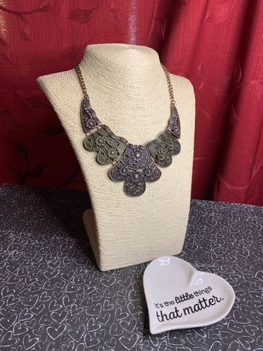 Embossed in whimsical floral detail, antiqued brass and copper plates connect below the collar for a statement making look. Features an adjustable clasp closure.  Sold as one individual necklace. Includes one pair of matching earrings.  Always nickel and lead free.