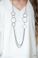 Load image into Gallery viewer, A collection of interlocking gunmetal rings give way to layers of mismatched gunmetal chains down the chest, creating a stunning tone-on-tone statement piece. Features an adjustable clasp closure.  Sold as one individual necklace. Includes one pair of matching earrings.  Always nickel and lead free.