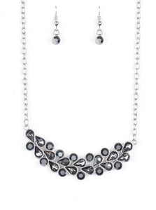 A collection of round and teardrop hematite and smoky rhinestones coalesce into a bowing silver pendant below the collar for a refined look. Features an adjustable clasp closure.  Sold as one individual necklace. Includes one pair of matching earrings.