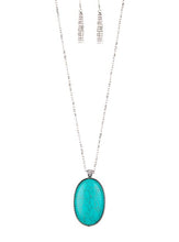 Load image into Gallery viewer, Chiseled into a tranquil oval, a dramatically over sized turquoise stone pendant swings from the bottom of a lengthened silver chain. Glassy white rhinestones dust the pendant's fitting for a refined flair. Features an adjustable clasp closure.  Sold as one individual necklace. Includes one pair of matching earrings.