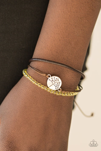 Mismatched strands of shiny cording and leather layer across the wrist. Featuring a strand of translucent yellow beading, a shimmery silver tree charm is knotted across the wrist, creating a whimsical centerpiece. Features an adjustable sliding knot closure.  Sold as one individual bracelet.  Always nickel and lead free.