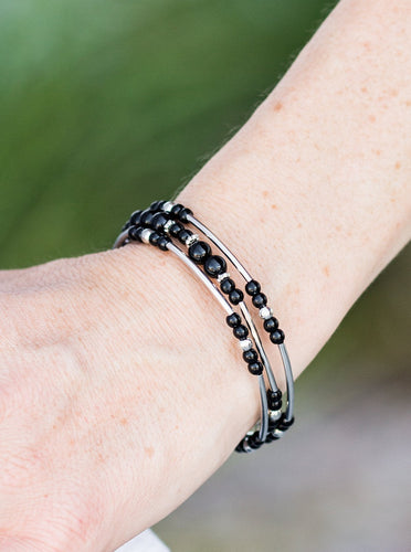 Shiny black beading and shimmery silver accents alternate along a coiled wire to create an earthy infinity wrap style bracelet.  Sold as one individual bracelet.