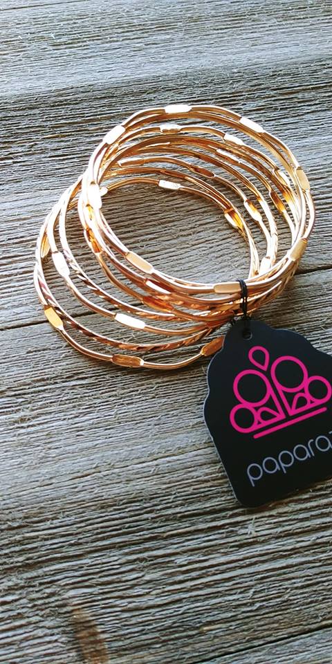 Featuring smooth and pressed faces, shimmery gold bangles stack across the wrist for a seasonal look.  Sold as one set of nine bracelets.  Always nickel and lead free.   Paparazzi Exclusive