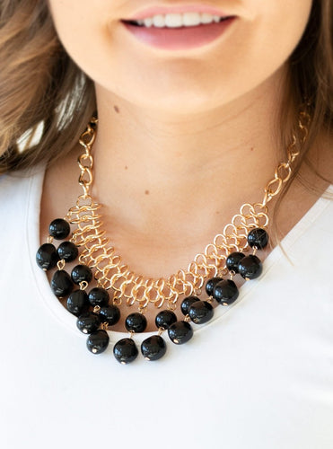 A collection of classic and imperfect black beads dangle from a web of interlocking gold links below the collar, adding a modern twist to the timeless palette. Features an adjustable clasp closure.  Sold as one individual necklace. Includes one pair of matching earrings.  