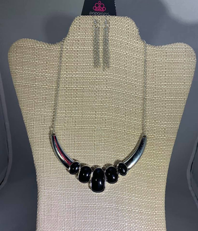 Gradually increasing in size at the center, a collection of abstract black beads are pressed into a shimmery half-moon frame, creating a colorful statement piece below the collar. Features an adjustable clasp closure.  Sold as one individual necklace. Includes one pair of matching earrings.  Always nickel and lead free.   Exclusive