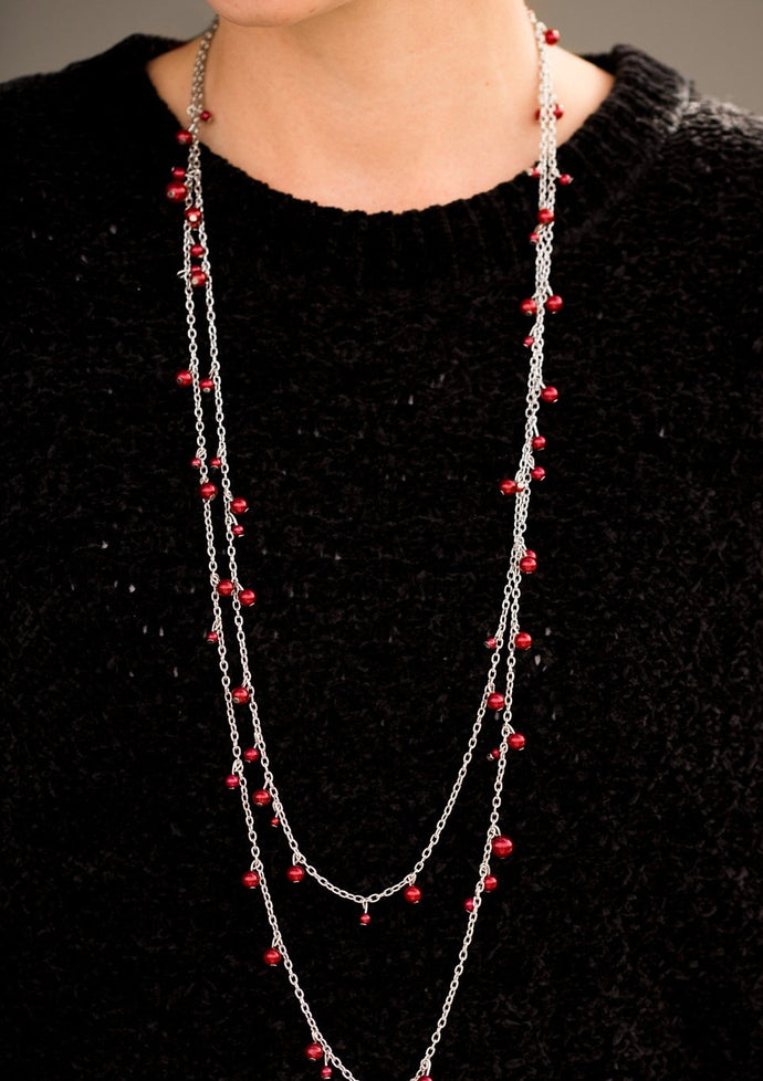 Varying in size, classic red pearls cascade along shimmery silver chains, creating a glamorous fringe. Features an adjustable clasp closure.  Sold as one individual necklace. Includes one pair of matching earrings.  Always nickel and lead free.