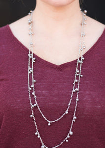 Varying in size, classic silver pearls cascade along shimmery silver chains, creating a glamorous fringe. Features an adjustable clasp closure.  Sold as one individual necklace. Includes one pair of matching earrings. 