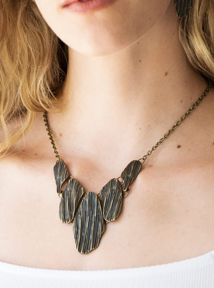 Engraved in antiqued textures, asymmetrical brass plates link below the collar for an edgy look. Features an adjustable clasp closure.  Sold as one individual necklace. Includes one pair of matching earrings.  Always nickel and lead free.