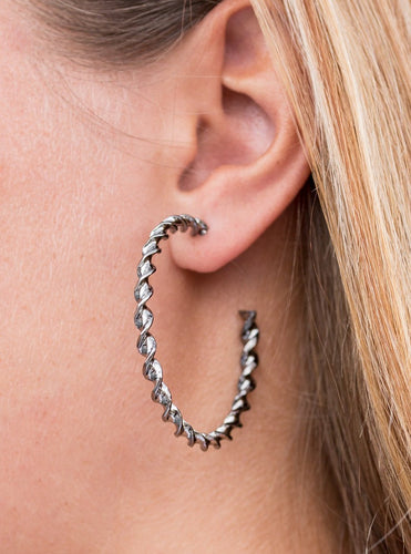 Glistening gunmetal twists into a twirling metallic ribbon. Brushed in an incandescent shimmer, the stunning gunmetal design evokes a refined style. Earring attaches to a standard post fitting. Hoop measures 2” in diameter.  Sold as one pair of hoop earrings. 
