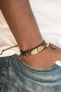 Mismatched brown leather bands layer across the wrist. Shimmery metallic accents slide along the centermost band, securing a shimmery brass feather charm in place for an urban finish. Features an adjustable sliding knot closure.  Sold as one individual bracelet.  Always nickel and lead free.