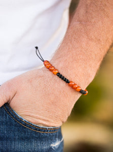 Orange stones are threaded along shiny black twine, creating a seasonal look around the wrist. Features an adjustable sliding knot closure.  Sold as one individual bracelet.