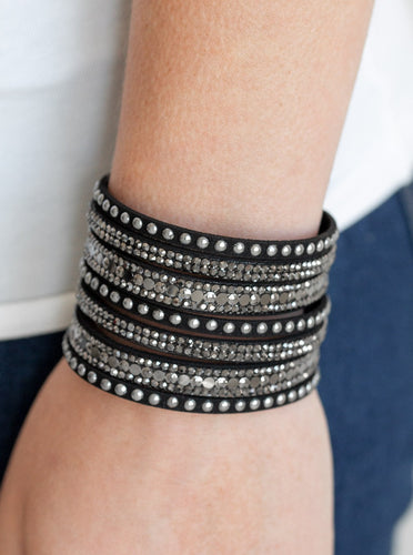 A thick black suede band has been spliced into glittery strands encrusted in a collection of dainty gunmetal studs, glittery hematite rhinestones, and flat gunmetal sequins for a sassy look. Features an adjustable snap closure.  Sold as one individual bracelet.  P9DI-URBK-199XX  