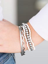 Load image into Gallery viewer, Varying in shimmer and shine, two silver bangles join a mishmash of stretchy silver and white beaded bracelets around the wrist for a seasonal look.  Sold as one set of five bracelets.