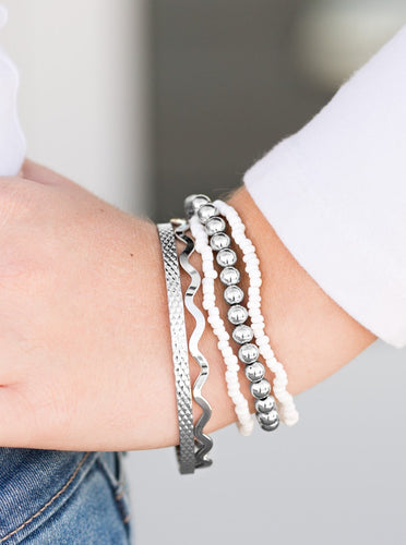 Varying in shimmer and shine, two silver bangles join a mishmash of stretchy silver and white beaded bracelets around the wrist for a seasonal look.  Sold as one set of five bracelets.