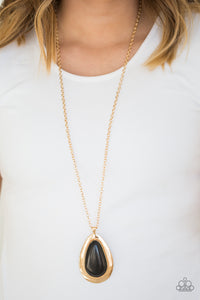 A dramatic black stone teardrop is pressed into a glistening gold frame radiating with rustic patterns. The impressive pendant swings from the bottom of a lengthened gold chain for a seasonal look. Features an adjustable clasp closure.  Sold as one individual necklace. Includes one pair of matching earrings.  Always nickel and lead free.