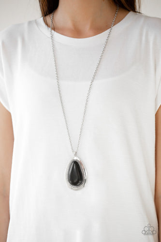 A dramatic black stone teardrop is pressed into a glistening silver frame radiating with rustic patterns. The impressive pendant swings from the bottom of a lengthened silver chain for a seasonal look. Features an adjustable clasp closure.  Sold as one individual necklace. Includes one pair of matching earrings.  Always nickel and lead free.