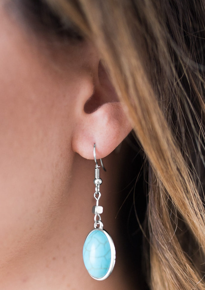 A smooth turquoise stone is pressed into a sleek silver frame, creating an earthy lure. Earring attaches to a standard fishhook fitting.  Sold as one pair of earrings.