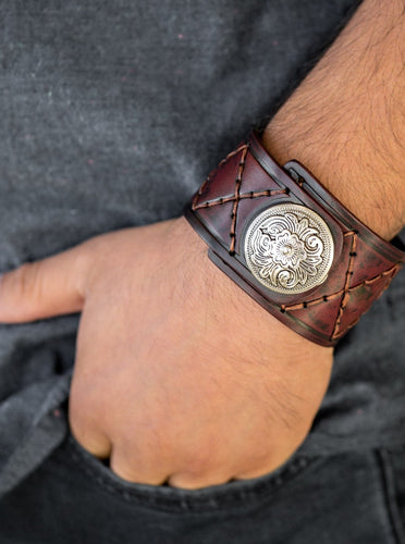 Featuring a flowery silver bead, a thick brown leather band has been stitched in diamond patterns across the front for a rugged look. Features an adjustable snap closure.  Sold as one individual bracelet.