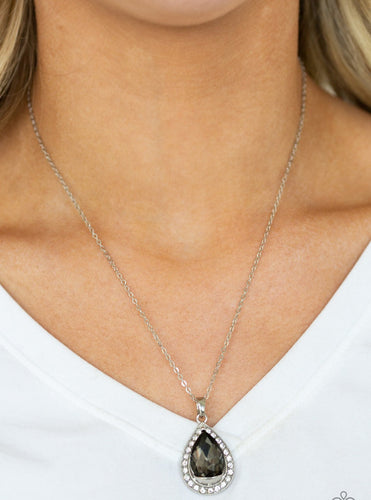 Featuring a regal teardrop cut, a smoky gem sits atop a silver frame encrusted in glassy white rhinestones. The royal pendant swings below the collar in a glamorous fashion. Features an adjustable clasp closure.  Sold as one individual necklace. Includes one pair of matching earrings.