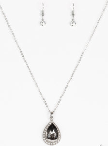 Featuring a regal teardrop cut, a smoky gem sits atop a silver frame encrusted in glassy white rhinestones. The royal pendant swings below the collar in a glamorous fashion. Features an adjustable clasp closure.  Sold as one individual necklace. Includes one pair of matching earrings.
