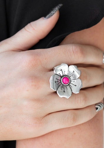 A bright pink bead is pressed into the center of a blooming silver flower radiating with antiqued details for a whimsical look. Features a stretchy band for a flexible fit.  Sold as one individual ring.