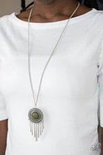 Load image into Gallery viewer, An earthy green stone is pressed into the center of a shimmery silver disc radiating with glistening tribal details. Swinging from the bottom of a lengthened silver chain, the bold pendant gives way to a fringe of delicately hammered silver rods for a wanderlust finish. Features an adjustable clasp closure.  Sold as one individual necklace. Includes one pair of matching earrings.  Always nickel and lead free.