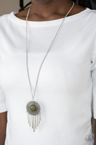 An earthy green stone is pressed into the center of a shimmery silver disc radiating with glistening tribal details. Swinging from the bottom of a lengthened silver chain, the bold pendant gives way to a fringe of delicately hammered silver rods for a wanderlust finish. Features an adjustable clasp closure.  Sold as one individual necklace. Includes one pair of matching earrings.  Always nickel and lead free.