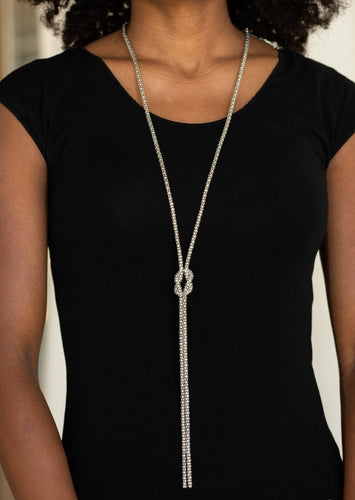 A glistening strand of lengthened silver popcorn chain delicately knots at the chest, creating an edgy tasseled pendant. Features an adjustable clasp closure.  Sold as one individual necklace. Includes one pair of matching earrings.  