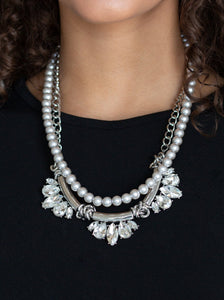 A classic strand of silver pearls and dramatic silvery chain drape below the collar. Infused with heavy metal accents, teardrop and marquise cut white rhinestone frames connect into a show-stopping fringe. Features an adjustable clasp closure.  Sold as one individual necklace. Includes one pair of matching earrings.  