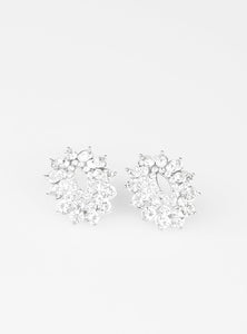 Varying in size, three stacks of glittery white rhinestones fan out from an airy center, coalescing into a stellar frame. Earring attaches to a standard post fitting.  Sold as one pair of post earrings.