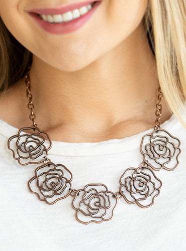 Brushed in an antiqued finish, stenciled copper rosebuds link below the collar for a seasonal fashion. Features an adjustable clasp closure.  Sold as one individual necklace. Includes one pair of matching earrings.