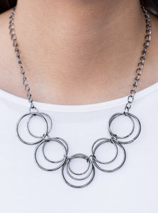 Brushed in an antiqued shimmer, glistening gunmetal hoops link below the collar in a bold industrial fashion. Features an adjustable clasp closure.  Sold as one individual necklace. Includes one pair of matching earrings.