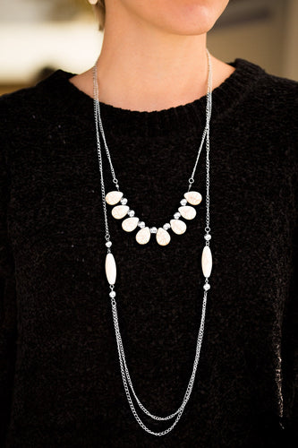 Chiseled into smooth teardrops, earthy white stones and classic silver beads are threaded along a skinny wire, creating an earthy fringe. Complimented with matching beads, cylindrical white stones give way to rows of silver chain for a bold layered finish. Features an adjustable clasp closure.  Sold as one individual necklace. Includes one pair of matching earrings.  