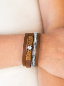 ﻿Brown leather strands layer across the wrist. Infused with silver chain and white rhinestone accents, brown cording knots around a leather strand, securing a solitaire white rhinestone in place for a whimsical finish. Features an adjustable clasp closure.  Sold as one individual bracelet.