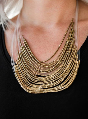 Strand after strand of shimmering brass seed beads fall together to create a bold statement piece. Features an adjustable clasp closure.  Sold as one individual necklace. Includes one pair of matching earrings.
